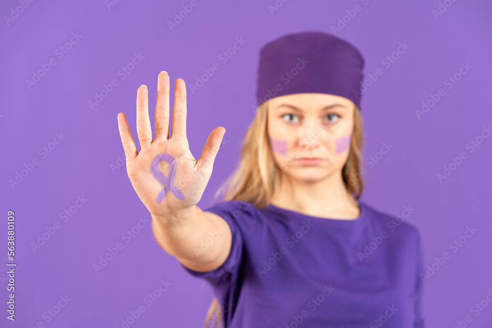 Young woman showing purple ribbon sign drawn on palm isolated on purple background. Feminism concept Young woman showing purple ribbon sign drawn on palm isolated on purple background. Feminism concept