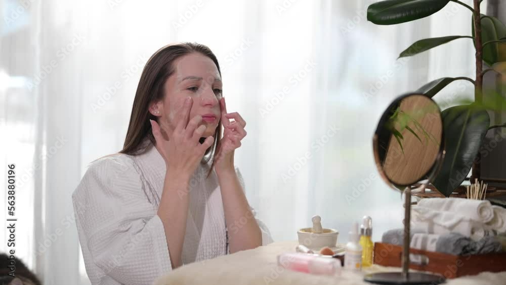 Caucasian woman applying sheet mask and rubbing her face with her fingers. Beauty and self care concept Caucasian woman applying sheet mask and rubbing her face with her fingers. Beauty and self care concept