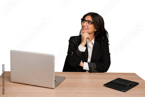 Young indian woman in a table with a laptop and tablet isolated looking sideways with doubtful and skeptical expression.