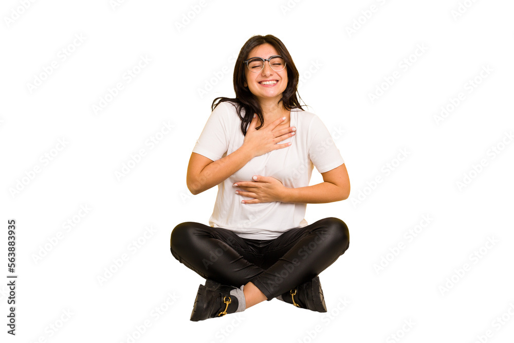 Young indian woman sitting on the floor cut out isolated laughs happily and has fun keeping hands on stomach. Young indian woman sitting on the floor cut out isolated laughs happily and has fun keeping hands on stomach.