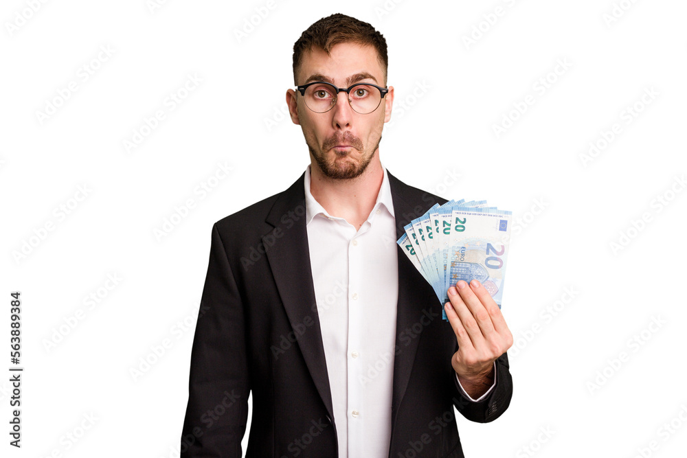 Young business caucasian man holding euro banknotes isolated cut out shrugs shoulders and open eyes confused. Young business caucasian man holding euro banknotes isolated cut out shrugs shoulders and open eyes confused.