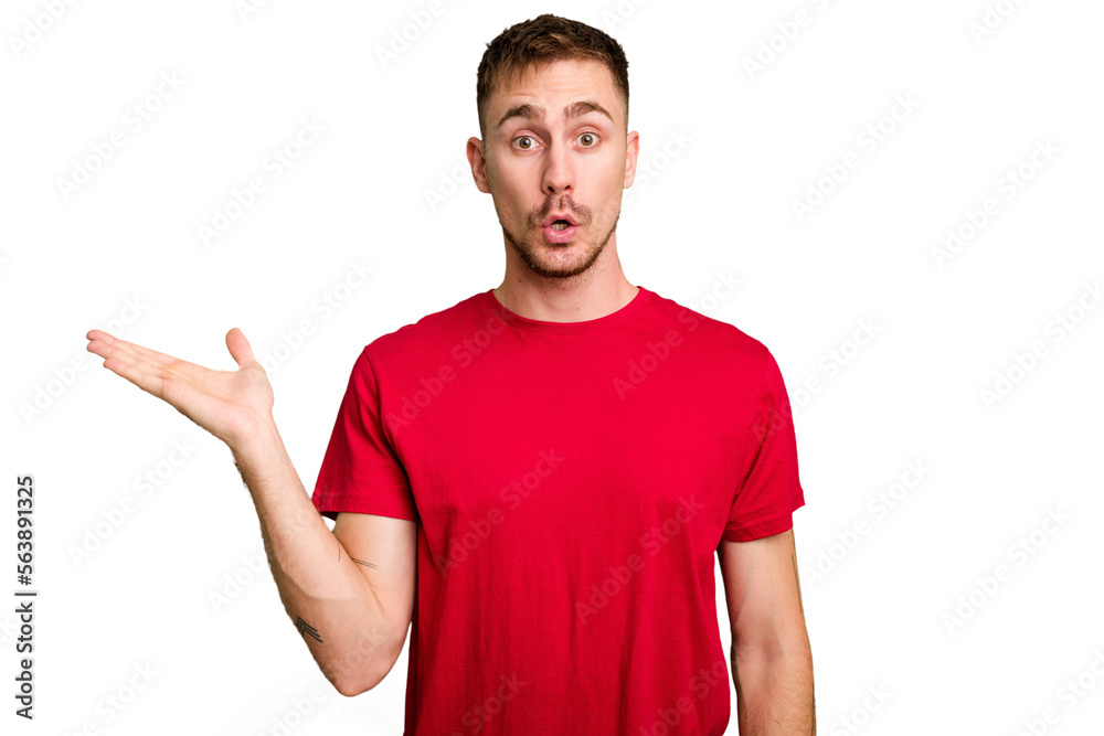 Young caucasian man cut out isolated impressed holding copy space on palm. Young caucasian man cut out isolated impressed holding copy space on palm.