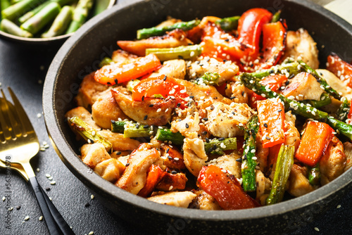 Chicken stir fry with vegetables and sesame in the skillet. Close up.