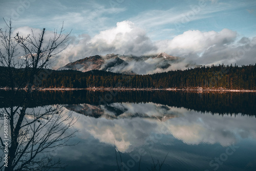 Bild auf Leinwand Cloudy sky and mountains reflected in the lake