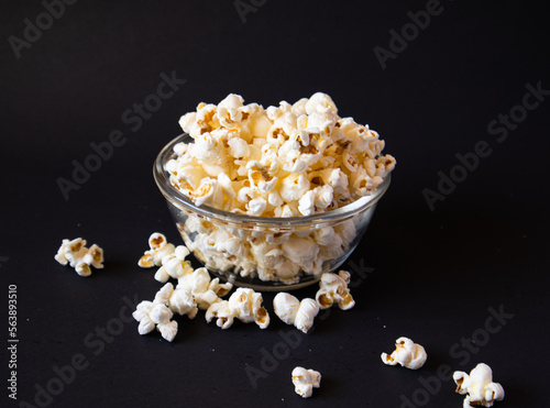 A popcorn-filled glass bowl, standing out against a dark and empty background