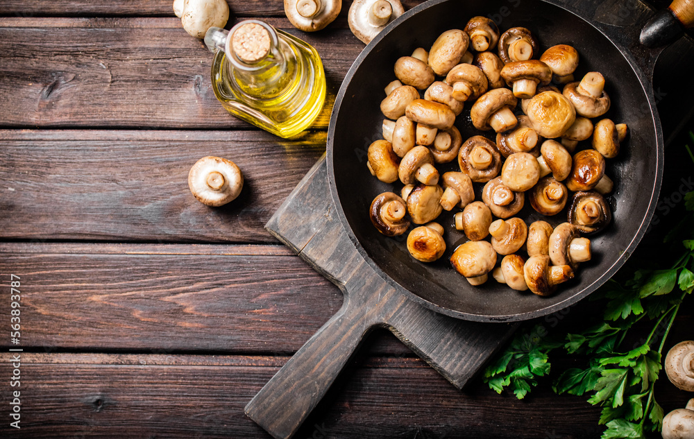 Fragrant homemade fried mushrooms in a frying pan on a cutting board. Fragrant homemade fried mushrooms in a frying pan on a cutting board.