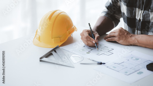 The architect is pointing to the house plans he has designed, he is meeting with engineers and clients to adjust the design before construction starts. Floor plan and interior design concepts.