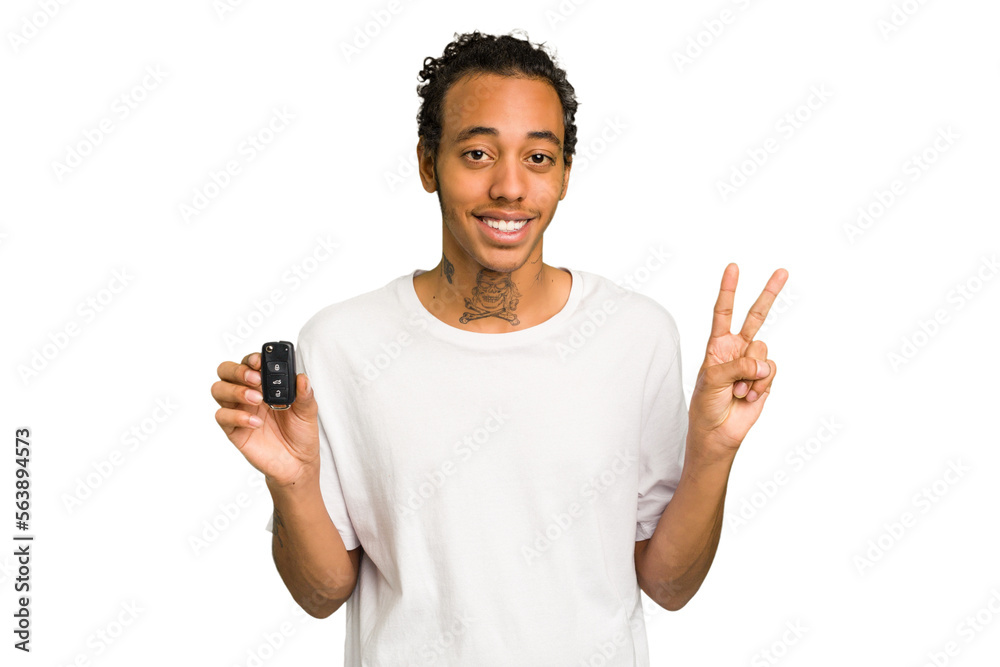 Young African American man holding car keys isolated joyful and carefree showing a peace symbol with fingers. Young African American man holding car keys isolated joyful and carefree showing a peace symbol with fingers.
