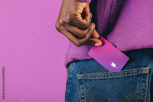 Paying with plastic: Man pulls a purple credit card from his pocket in a studio photo