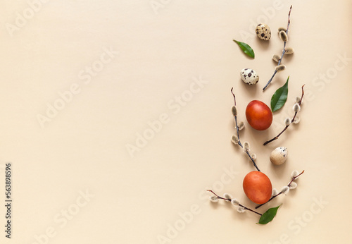 Easter composition with fluffy willow branches, green leaves and painted red Easter eggs on a light background. Empty space for congratulatory text or holiday message. Flat lay, copy space, mock up photo