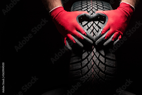 Fototapeta Naklejka Na Ścianę i Meble -  Car tire service and hands of mechanic holding new tyre on black background with copy space for text