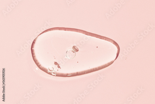 Transparent Liquid gel cosmetic smudge texture. Clear liquid gel with bubbles drop isolated on pink background