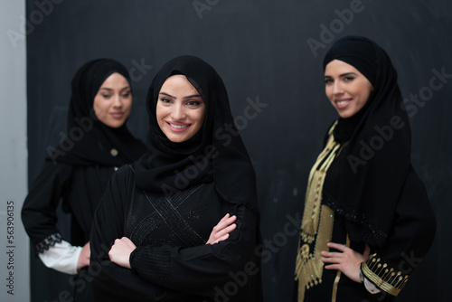 Group portrait of beautiful Muslim women in a fashionable dress with hijab isolated on black background