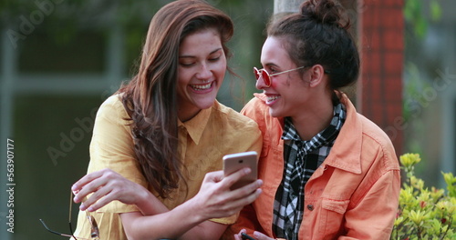 Two young women in front of smartphone laughing and smiling