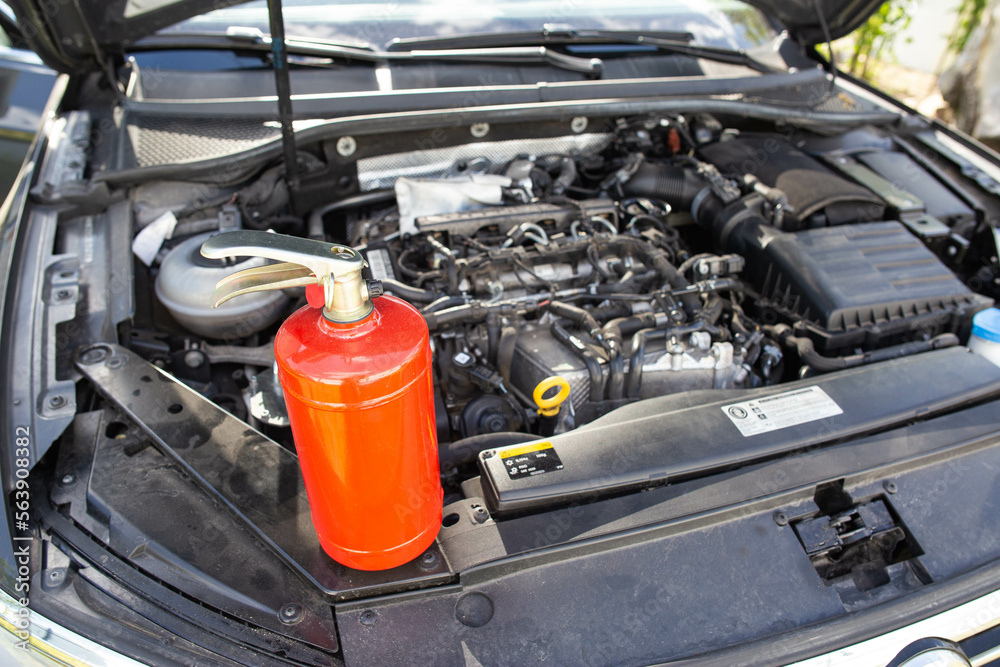 Car fire extinguisher on the background of the car engine