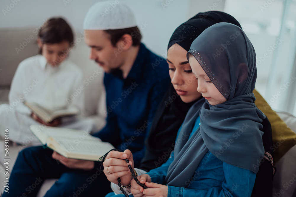 Happy Muslim family enjoying the holy month of Ramadan while praying and reading the Quran together in a modern home Happy Muslim family enjoying the holy month of Ramadan while praying and reading the Quran together in a modern home