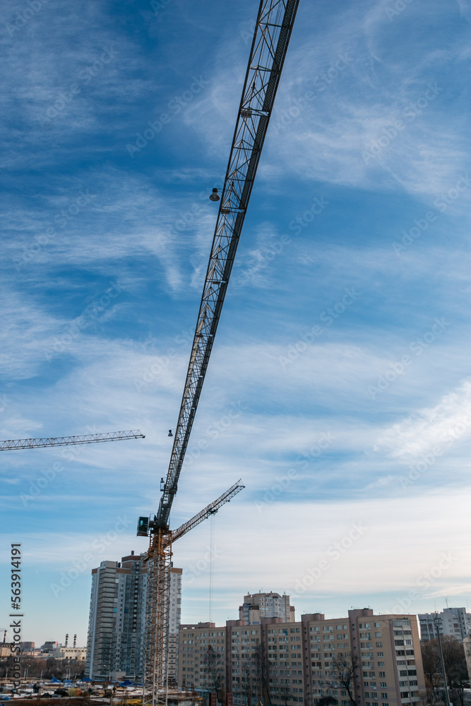 Construction cranes against the blue sky. The concept of building a new area. Construction of a new building. The concept of building a new area. The work of building cranes.