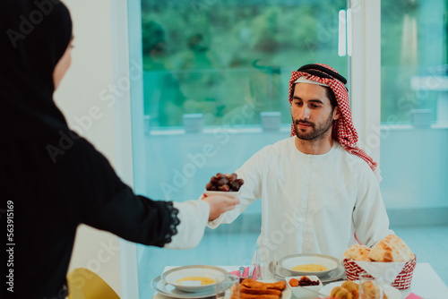 Modern multiethnic muslim family sharing a bowl of dates while enjoying iftar dinner together during a ramadan feast at home