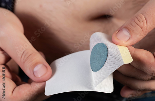 A modern medical patch for prostatitis and urinary tract infections. A man glues a urological patch on his stomach, close-up
