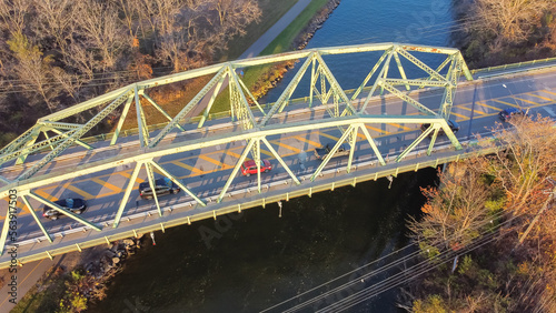 Aerial view truss bridge with car traffic over Erie Canal with colorful fall foliage in late afternoon light Pittsford, New York