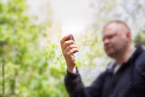 A man in the forest with a navigator in his hand. Location determination. The mushroom picker got lost in the forest. Compass and survival. Copy space for text, blurry photo