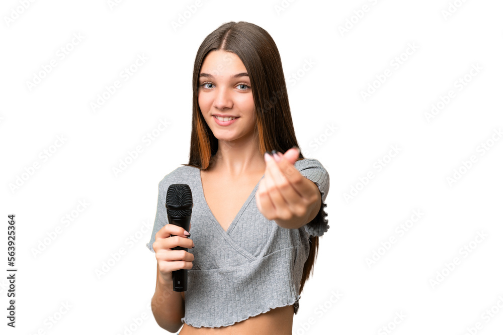 Teenager singer girl picking up a microphone over isolated background making money gesture Teenager singer girl picking up a microphone over isolated background making money gesture