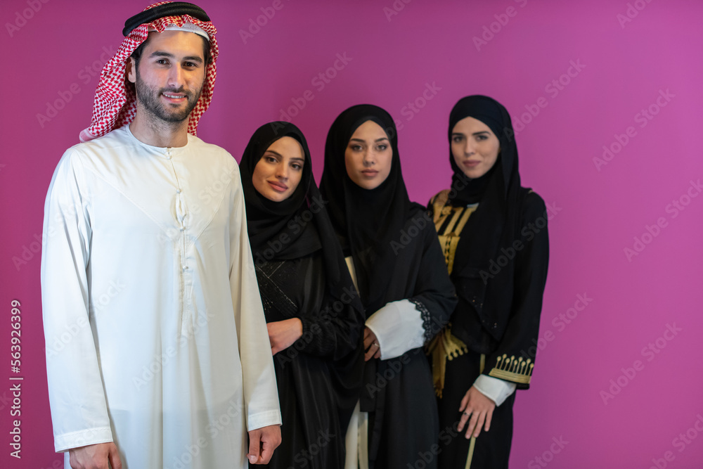Group portrait of young Muslim people Arabian men with three Muslim women in a fashionable dress with hijab isolated on a pink background