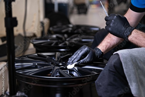 Obraz na płótnie Employee of a car detailing studio applies a protective ceramic coating to a car rim w salonie