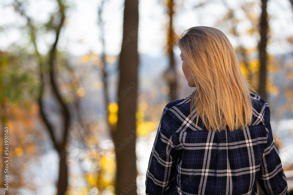 A woman stands with her back against the background of autumn. A girl walking in the forest in sunset light. Back to the camera, autumn life A woman stands with her back against the background of autumn. A girl walking in the forest in sunset light. Back to the camera, autumn life