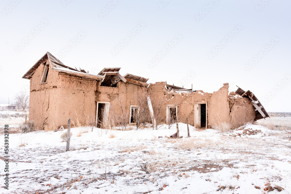 Abandoned two story red adobe in snow, Garcia, CO