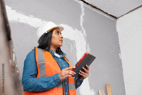A young female South Asian construction worker uses tablet to log project