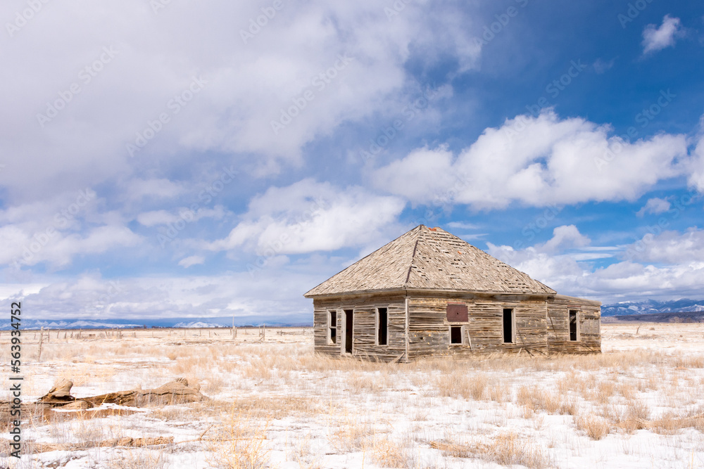 Abandoned wooden homestead on potato farm, San Luis Valley, CO, mountain range, blue sky, snow, and clouds on a winter day Abandoned wooden homestead on potato farm, San Luis Valley, CO, mountain range, blue sky, snow, and clouds on a winter day