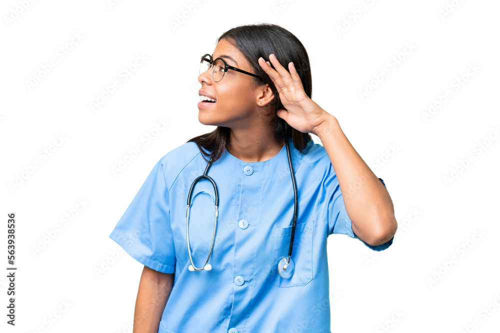 Young African american nurse woman over isolated background listening to something by putting hand on the ear Young African american nurse woman over isolated background listening to something by putting hand on the ear