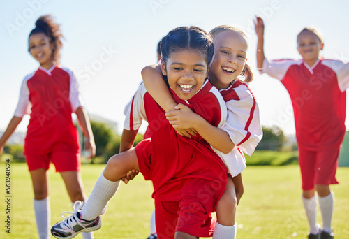 Soccer, girl celebration and field with happy piggyback, team building support and solidarity for winning game. Female kids, sports diversity and celebrate with friends, teamwork and goal in football photo