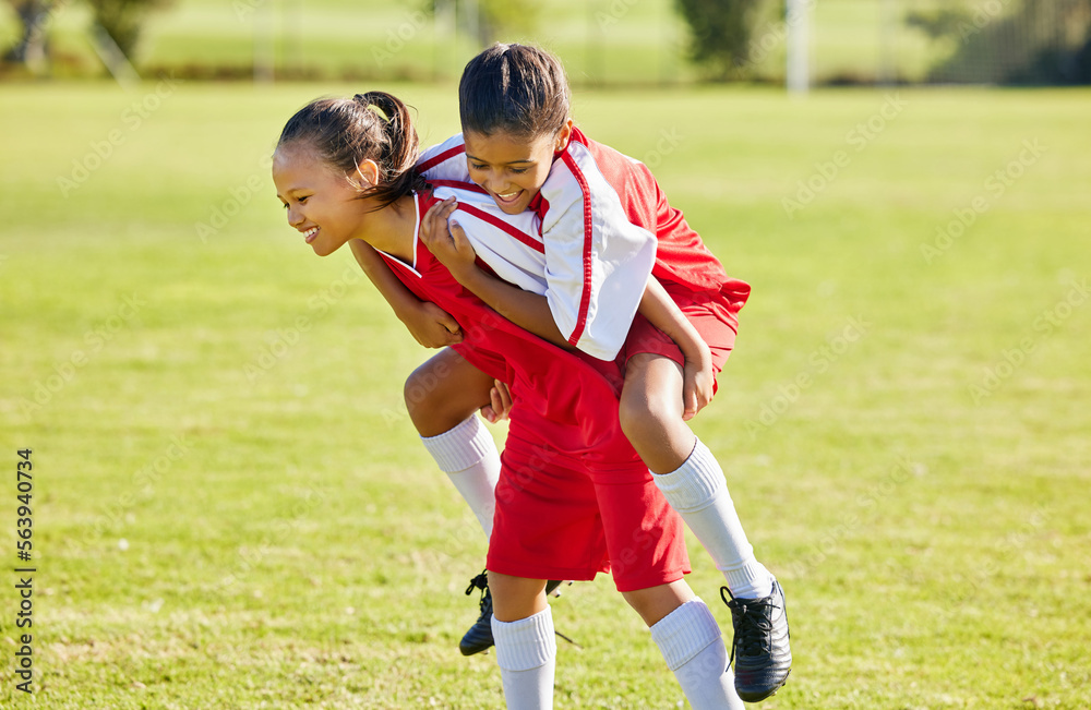 Obraz premium Girl soccer player, happy celebration and grass with piggyback for goal, teamwork and winning contest. Young female kids, winner and celebrate with support, solidarity and happiness at soccer field