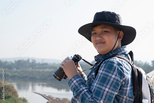 Asian boys are using binoculars to do the birds' watching in tropical forest during summer camp, idea for learning creatures and wildlife animals and insects outside the classroom. © Sophon_Nawit