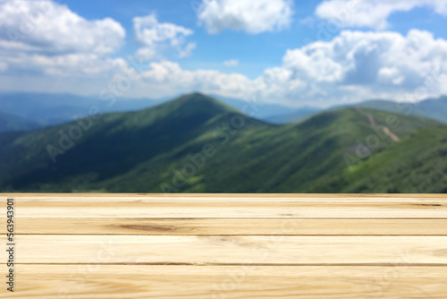 Wooden table, free space, green mountain valley, blue sky and clouds, light colors, kopi space, summer mountain landscape.