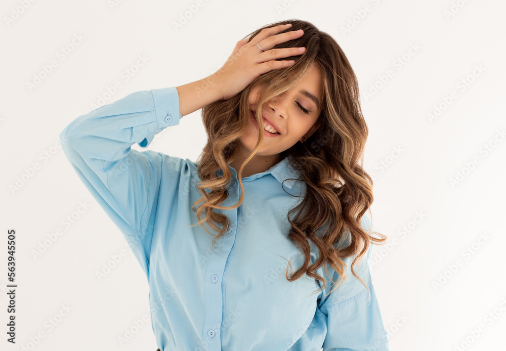 Laughing woman in blue shirt with wavy hair over white wall. Toothy smile Laughing woman in blue shirt with wavy hair over white wall. Toothy smile