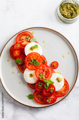 Classic italian salad caprese served in original form with different tomatoes, mozarella, pesto sauce and basil