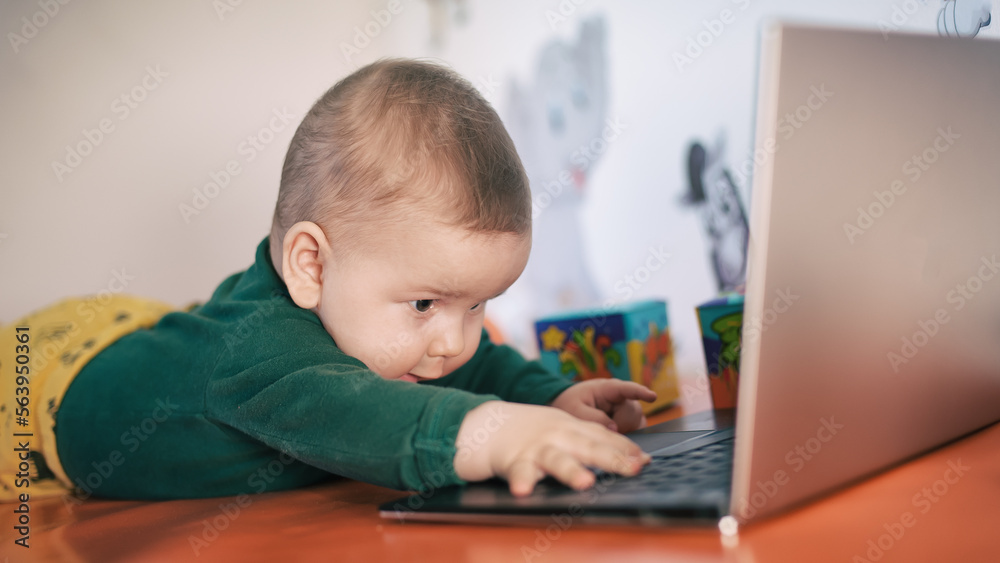 Portrait of baby boy using a laptop computer at his business office - game room. Technology and toys concept. Funny babies Portrait of baby boy using a laptop computer at his business office - game room. Technology and toys concept. Funny babies