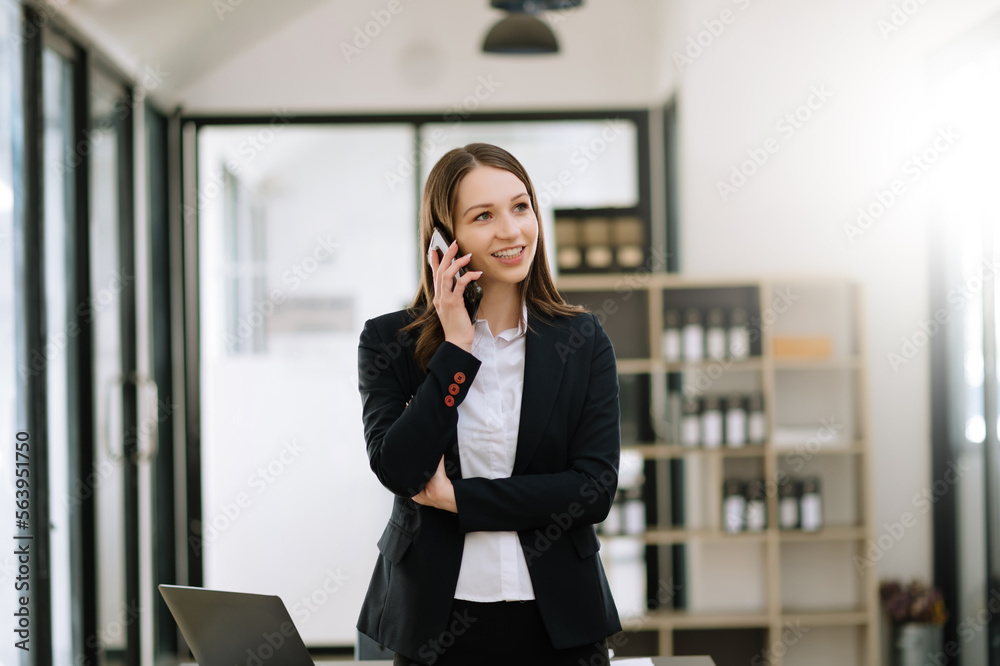 Business woman Talking on the phone and using a laptop with a smile while sitting at office. Business woman Talking on the phone and using a laptop with a smile while sitting at office.