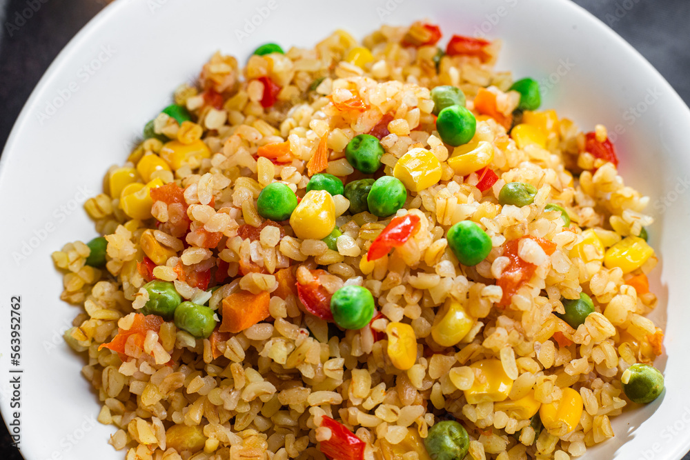 Bulgur with vegetables in a white plate close-up Bulgur with vegetables in a white plate close-up