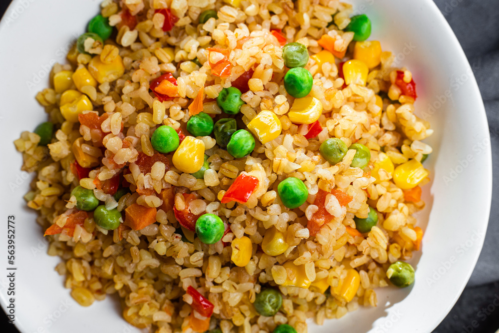 Bulgur with vegetables in a white plate close-up Bulgur with vegetables in a white plate close-up