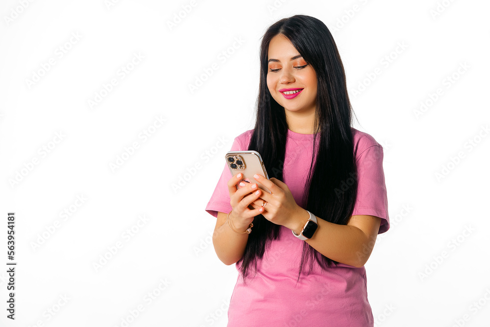© Red Cristal - Smiling girl using mobile phone, holding telephone, looks happy, stands over white background. Pretty brunette female holding cell phone and reading funny message she received from boyfriend © Red Cristal - Smiling girl using mobile phone, holding telephone, looks happy, stands over white background. Pretty brunette female holding cell phone and reading funny message she received from boyfriend
