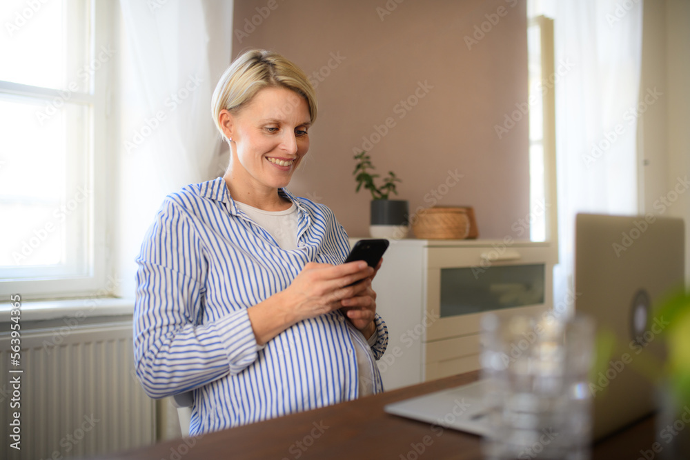 Pregnant woman having home office, scrolling her phone. Pregnant woman having home office, scrolling her phone.
