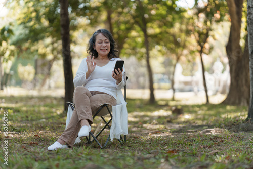 Happy senior asian woman at outdoor park and talking on video call with family