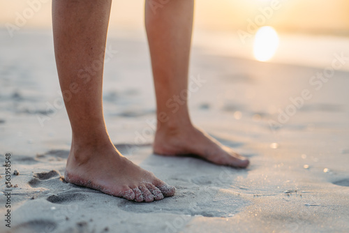 Close-up of womans feet in sand, at sea.