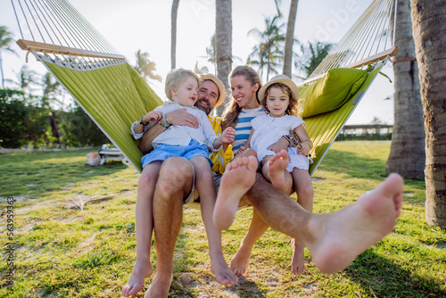 Young family with little kids enjoying their holiday in exotic country, lying in hammock.