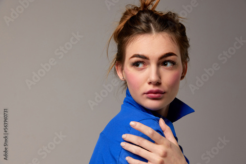 Fashionable stylish emotional woman wearing blue shirt posing over gray background. Model with vivid facial expression. Concept of fashion, style, youth, beauty photo