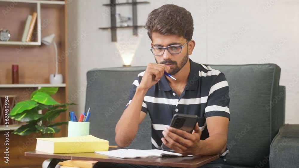 Young man using mobile phone for writing notes at home while listening online class - concept of e-learning, dedication and intelligence. Young man using mobile phone for writing notes at home while listening online class - concept of e-learning, dedication and intelligence.